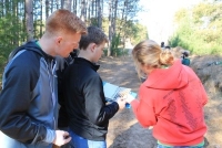 Kids looking at a book on a wooded trail